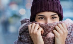 Woman in cold winter weather covering her face with a scarf, needing microneedling.